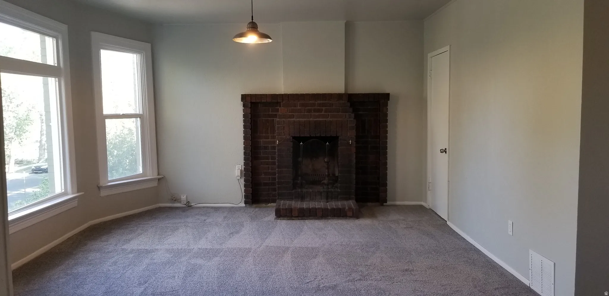 Living area featuring a brick fireplace, light gray wall paint, and gray carpeting