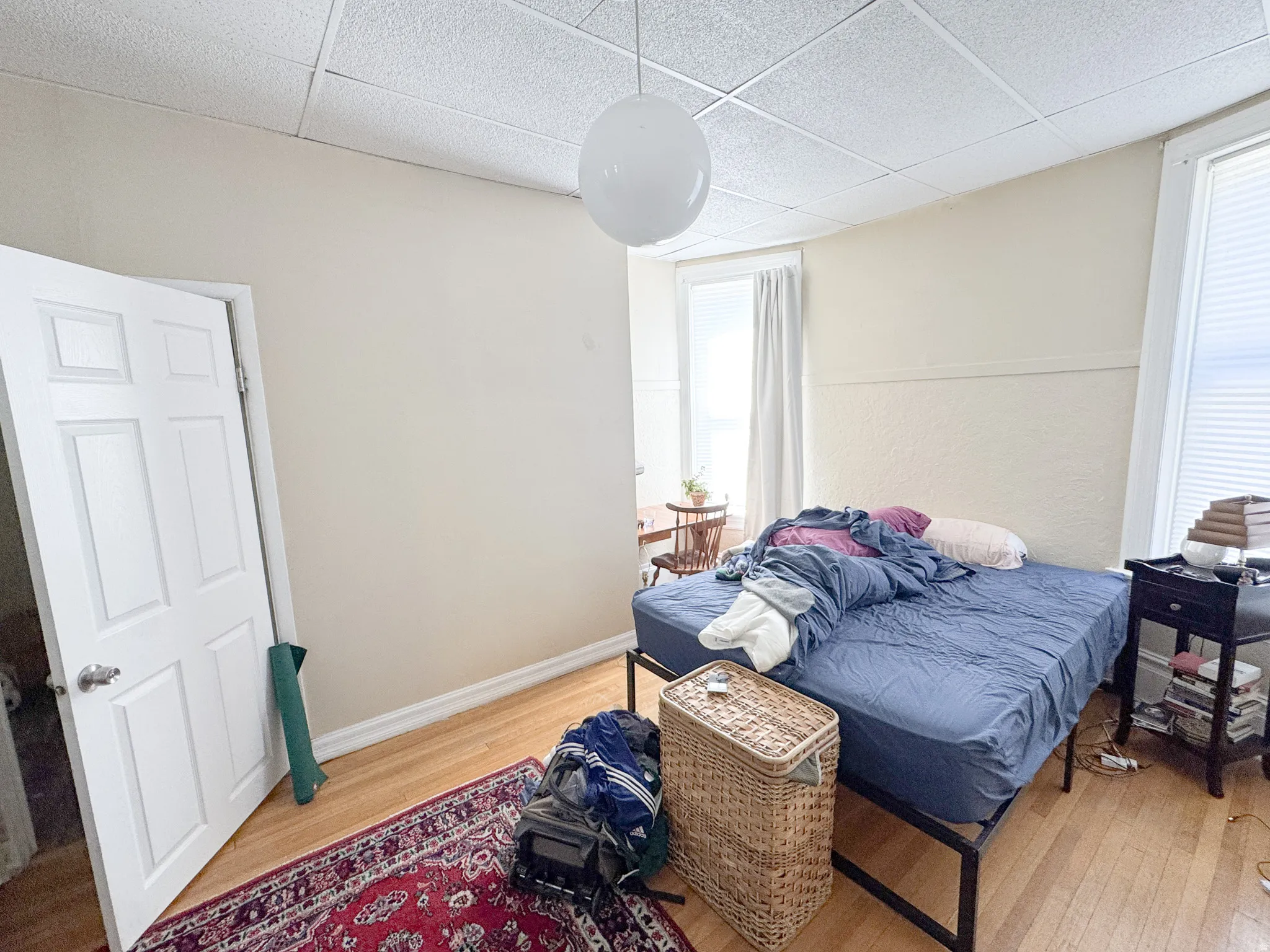 Room featuring hardwood flooring, white paneled door, and a grid-patterned ceiling