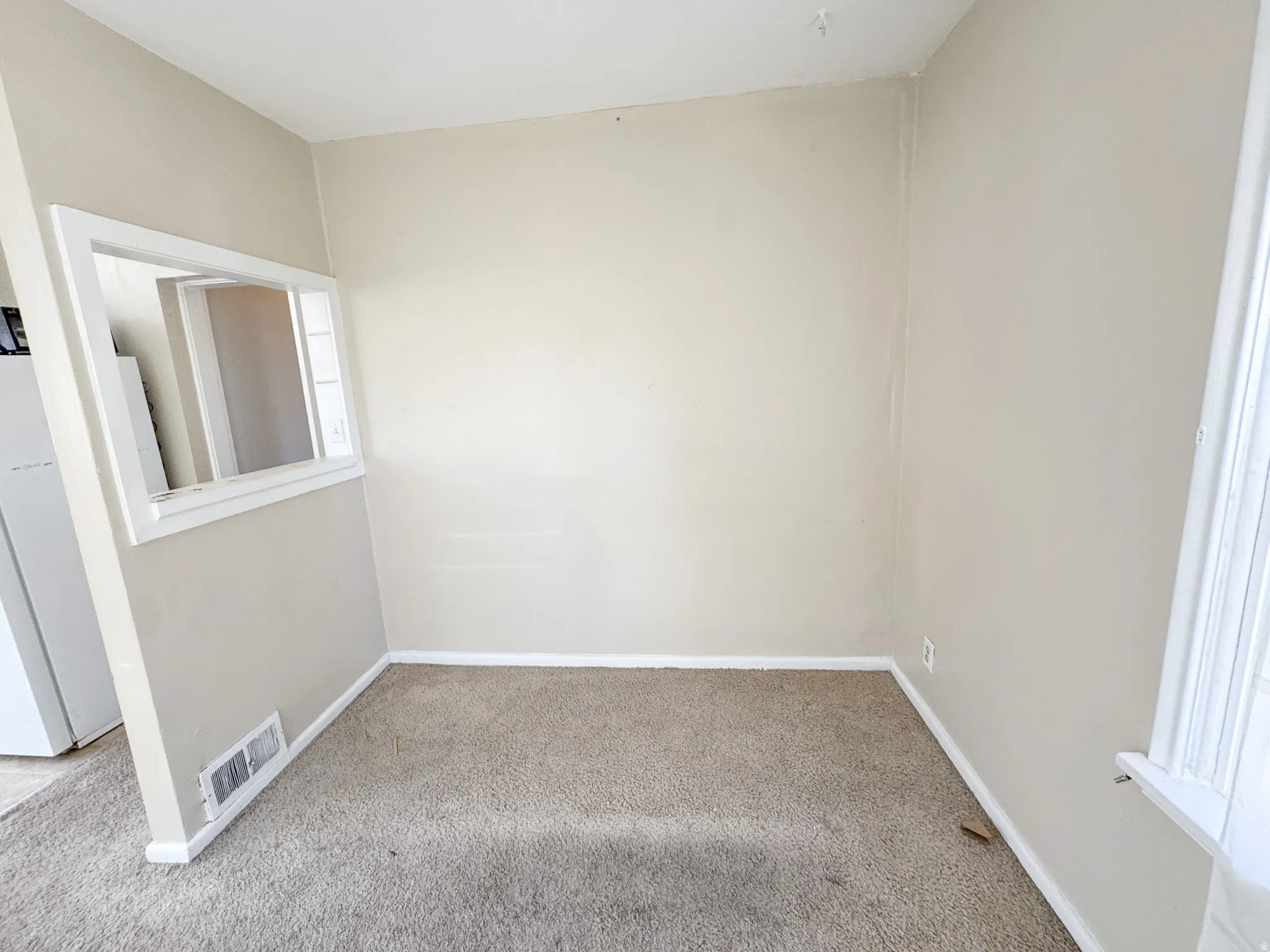 Neutral wall paint, light brown carpeting, white trim, and a pass-through window