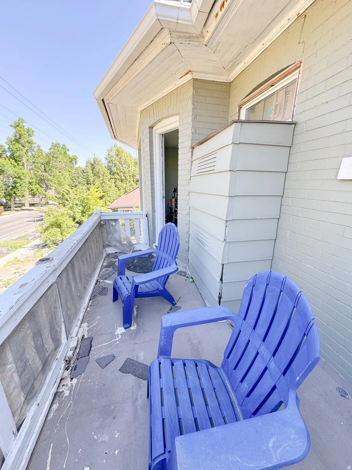 Exterior balcony featuring a brick facade, white trim, and a concrete floor