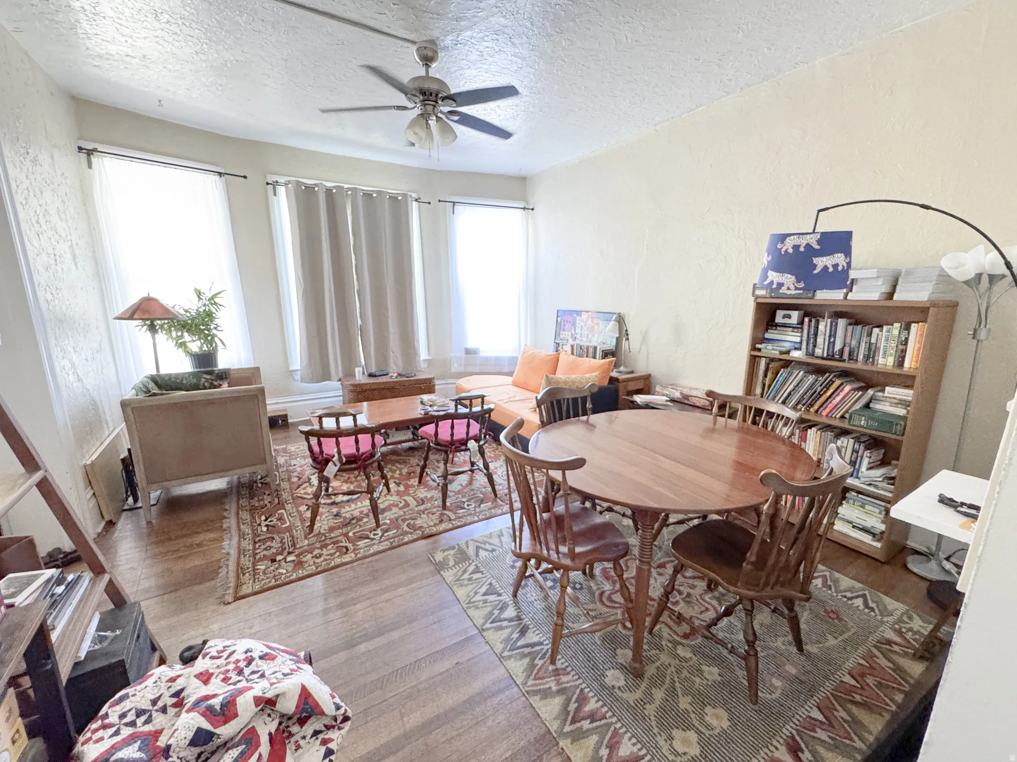 Spacious room featuring wood-finish flooring, a ceiling fan, and multiple windows