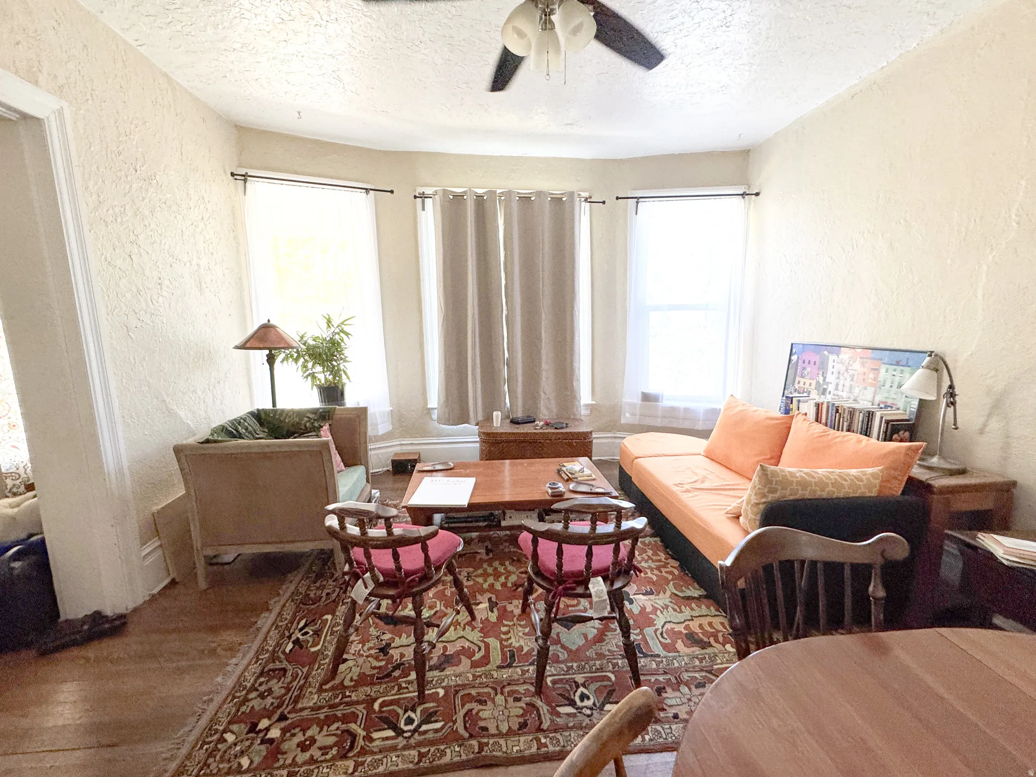 Living area featuring a ceiling fan with light kit, textured wall finish, and wood-finish flooring