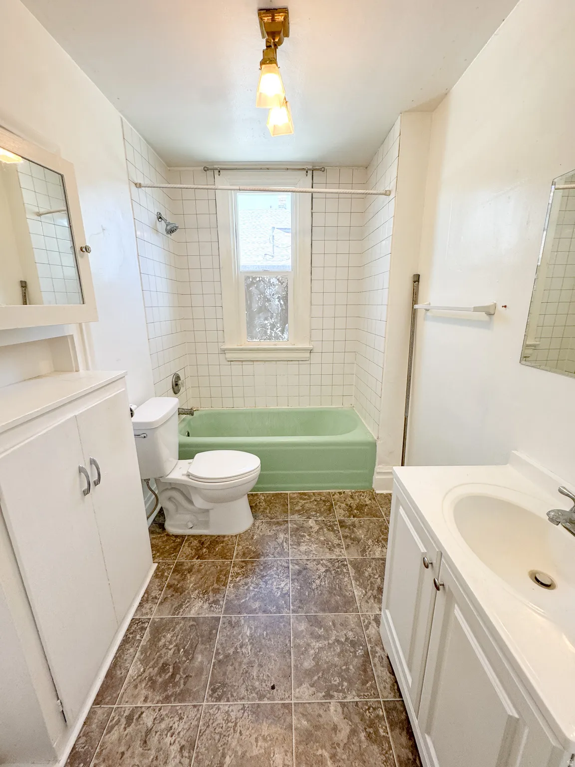 Bathroom featuring a green bathtub with white subway tile surround and a window