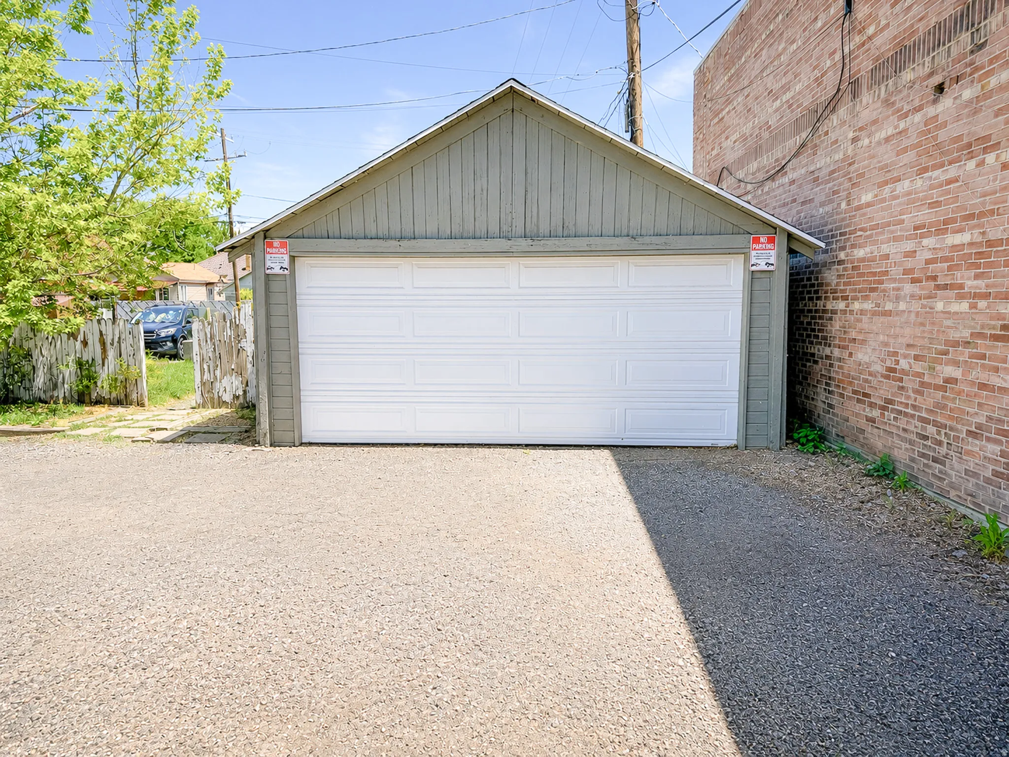 Two-car garage with a white panel door, featuring a pitched roof and light green siding