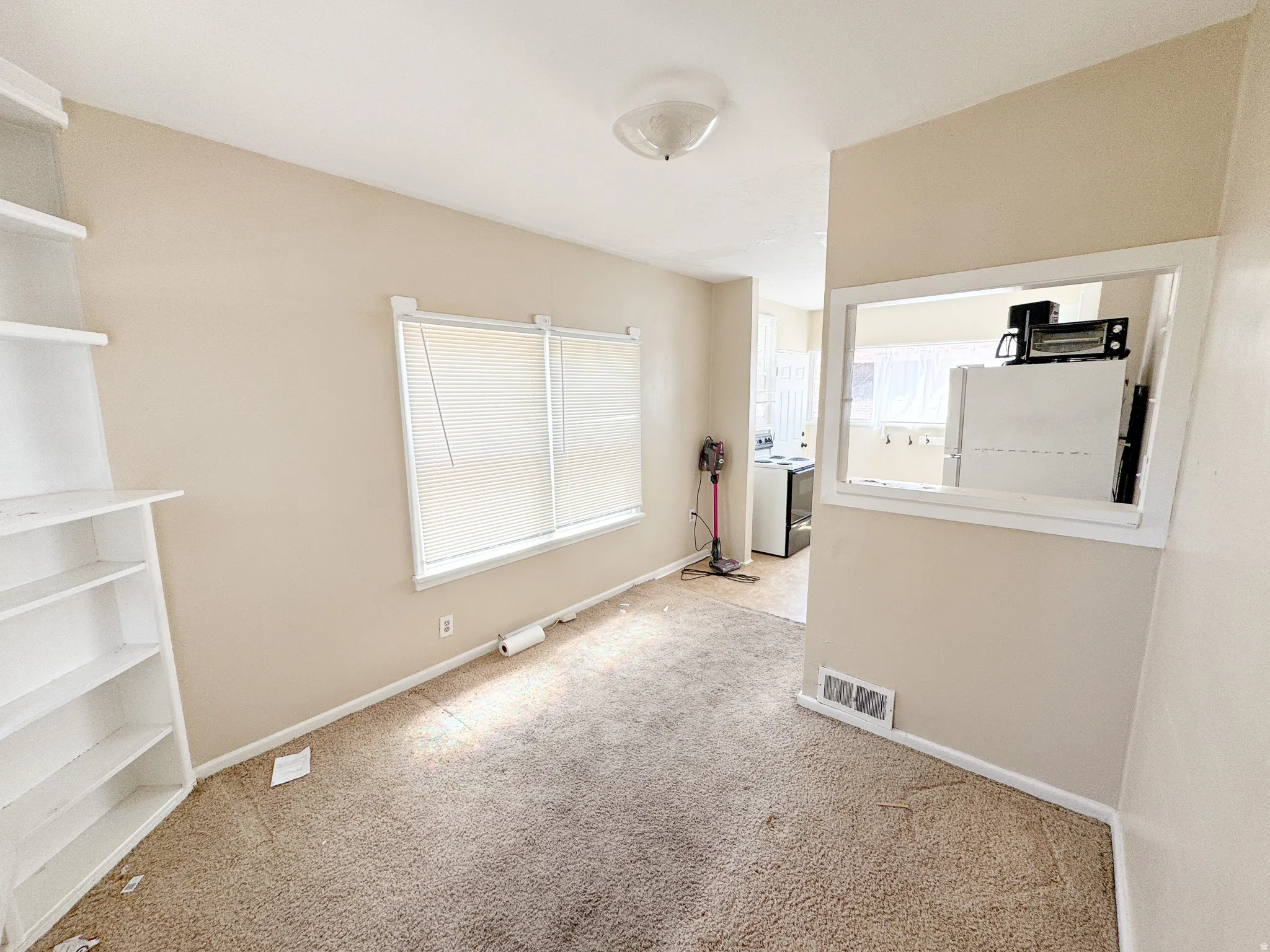 Carpeted living area featuring a built-in shelving unit and two windows with blinds