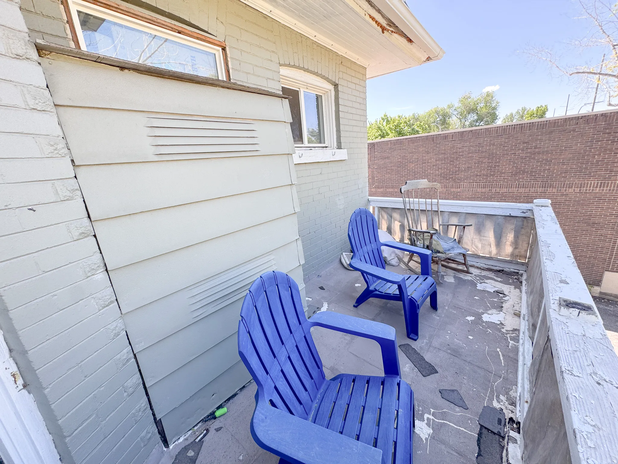 Upper-level exterior balcony with a partial brick facade and horizontal siding