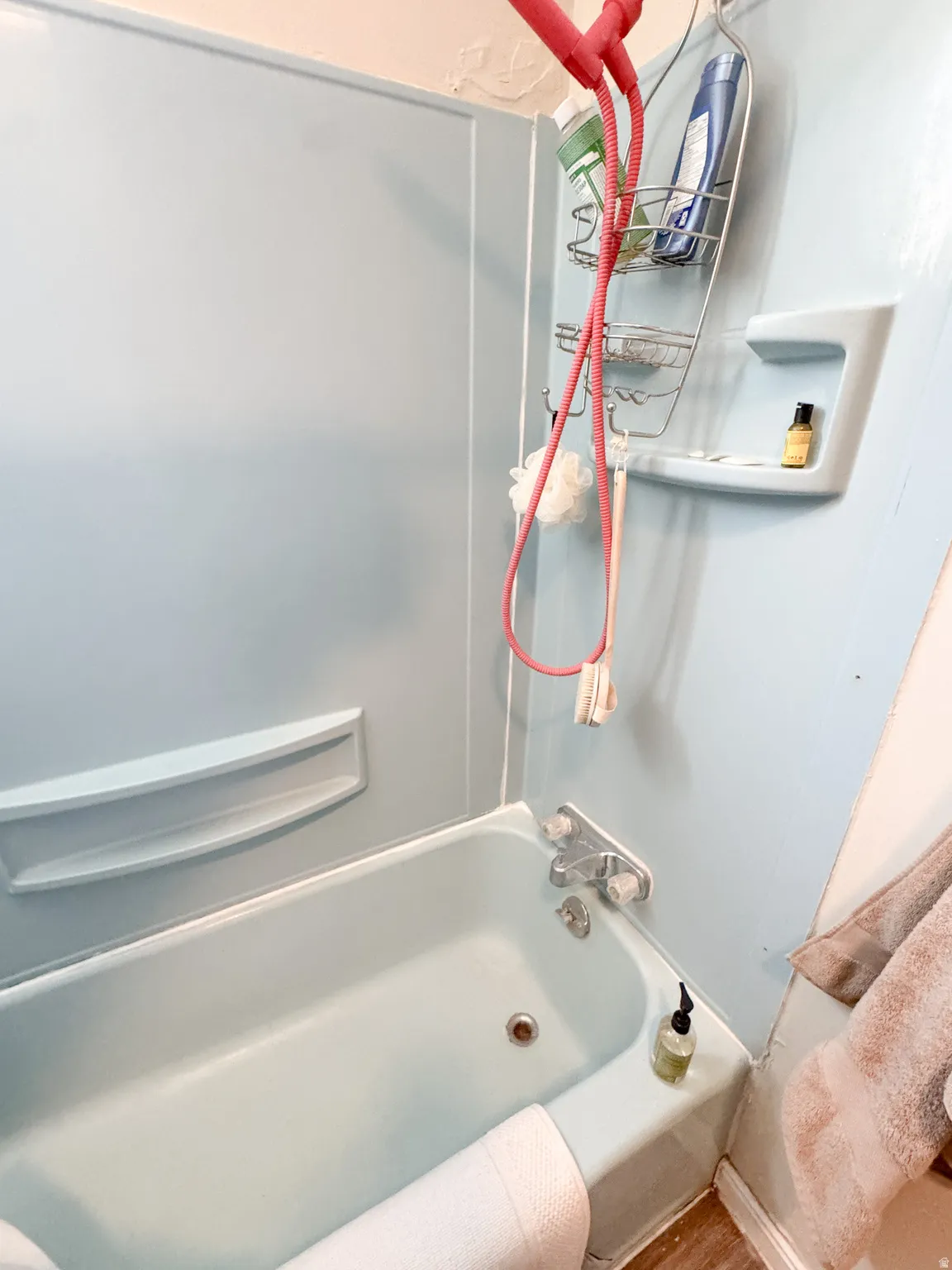 Bathtub with integrated shower surround, featuring a built-in soap dish and chrome fixtures