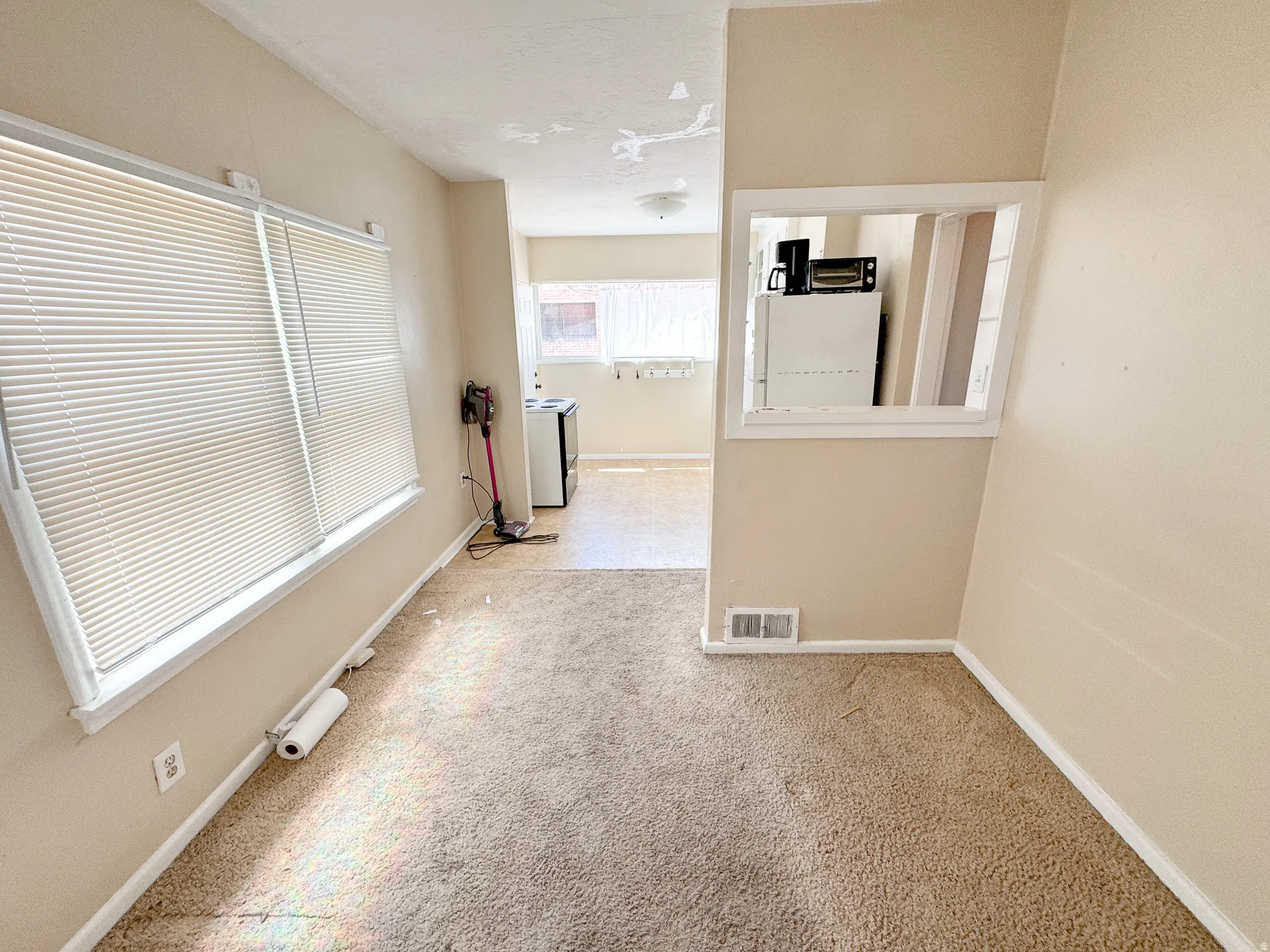 Carpeted room with a wide window featuring blinds
