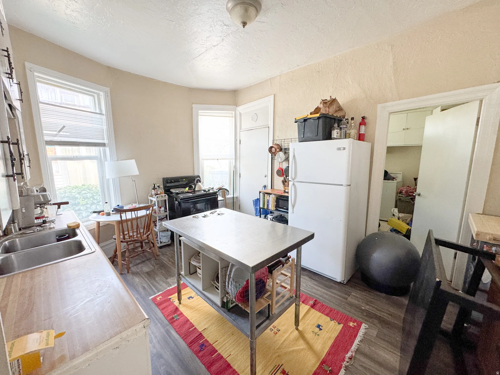 Kitchen featuring wood-finish flooring, dual windows, and an adjacent utility area