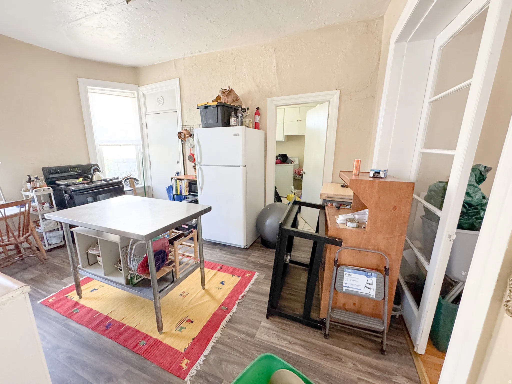 Kitchen area featuring wood-finish flooring, white appliances, and a built-in corner cabinet