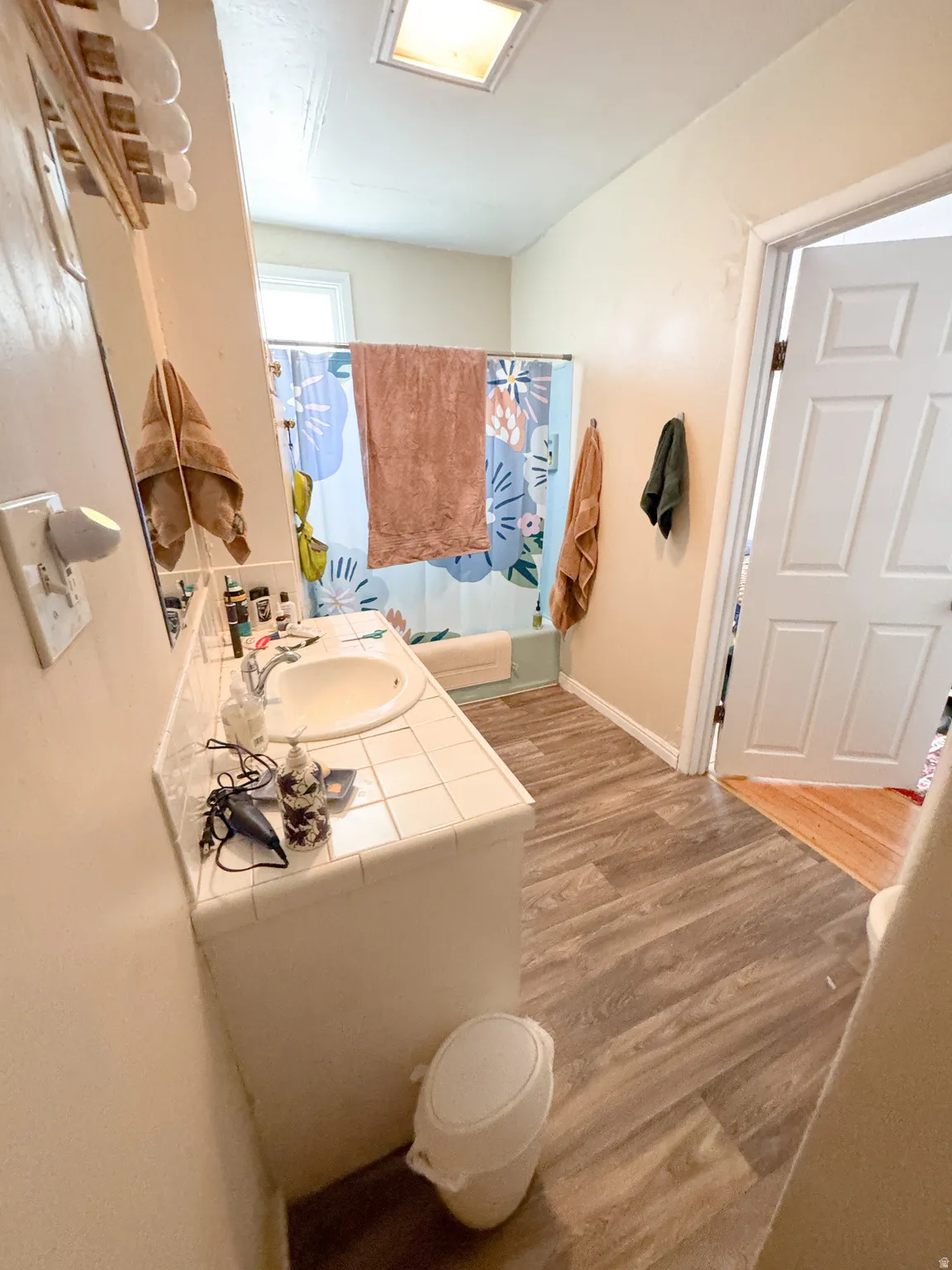 Bathroom featuring a vanity with a drop-in sink, tiled countertop, and wood-finish flooring