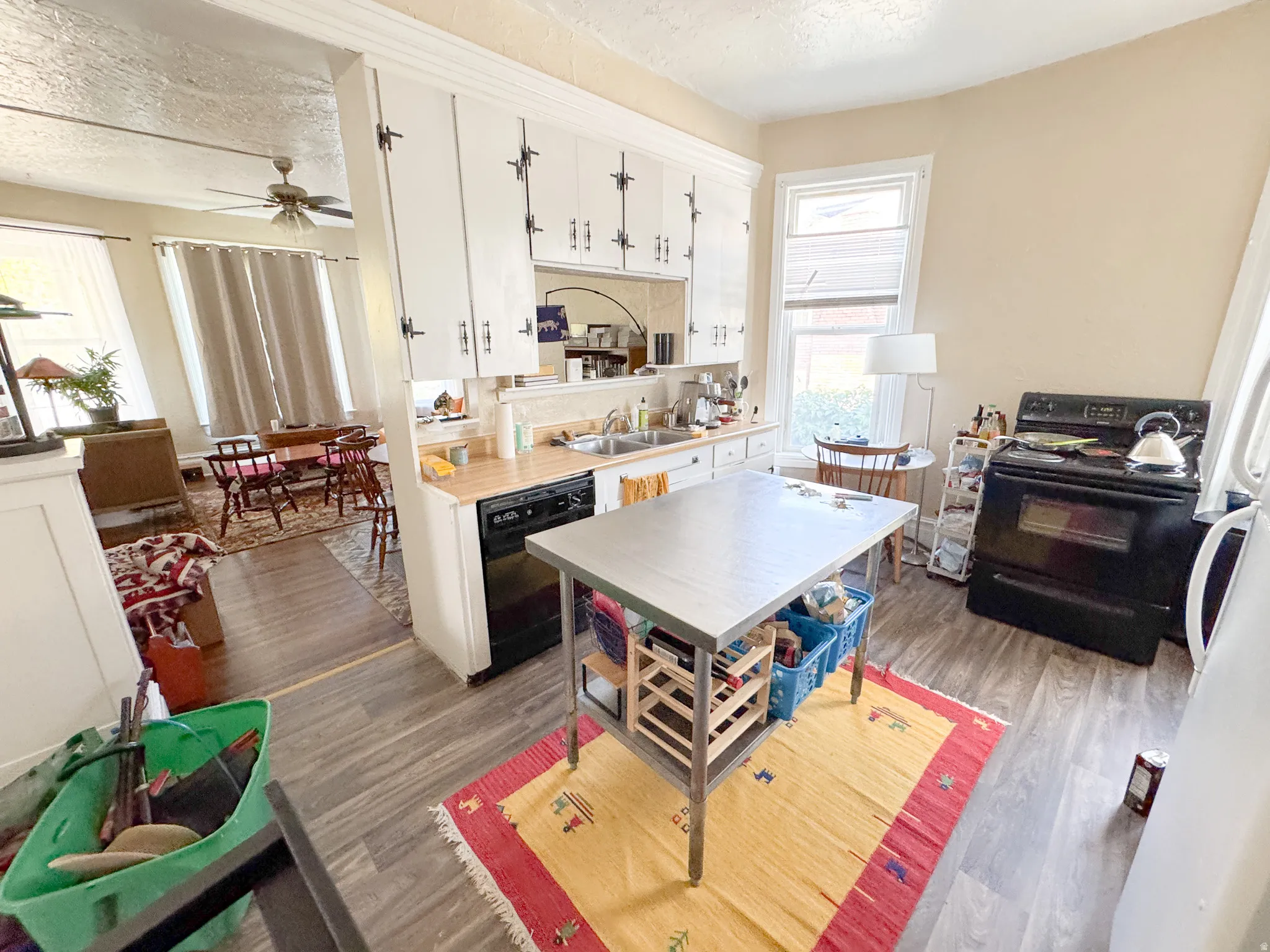 Kitchen featuring white cabinetry, wood-finish flooring, a stainless steel sink, and black appliances