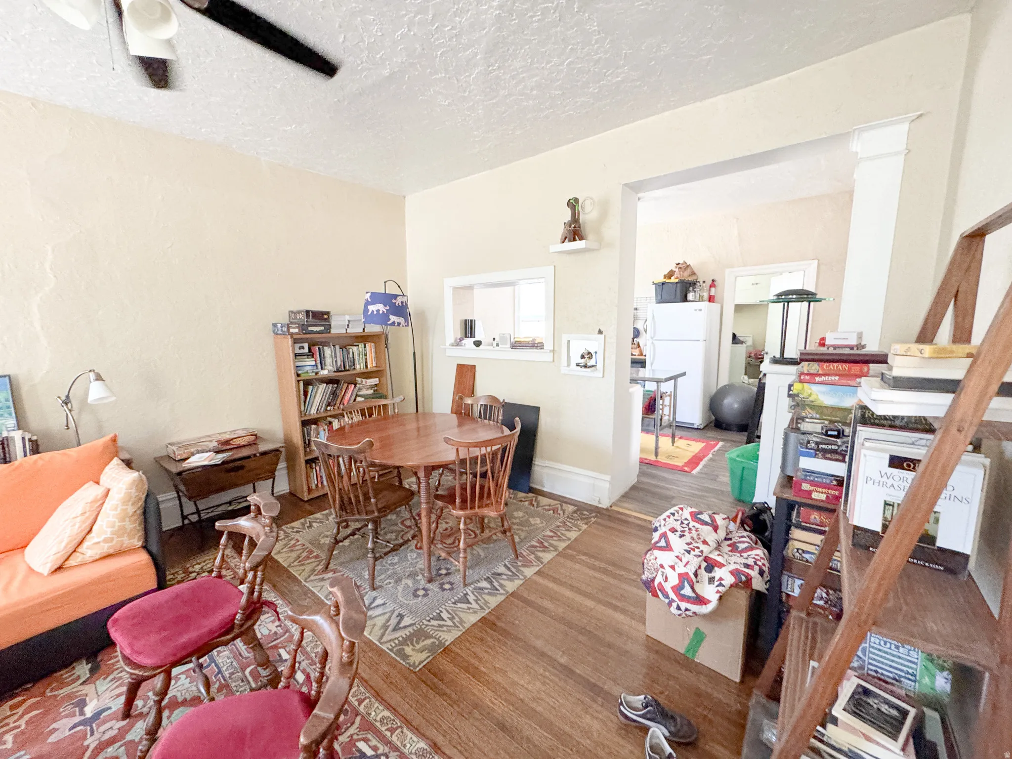 Hardwood-style flooring throughout the main living area, featuring a decorative ceiling fan and an arched doorway leading to an additional space
