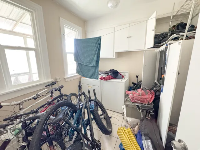 Utility room featuring white shaker cabinetry, two double-hung windows, a washer, and tile flooring