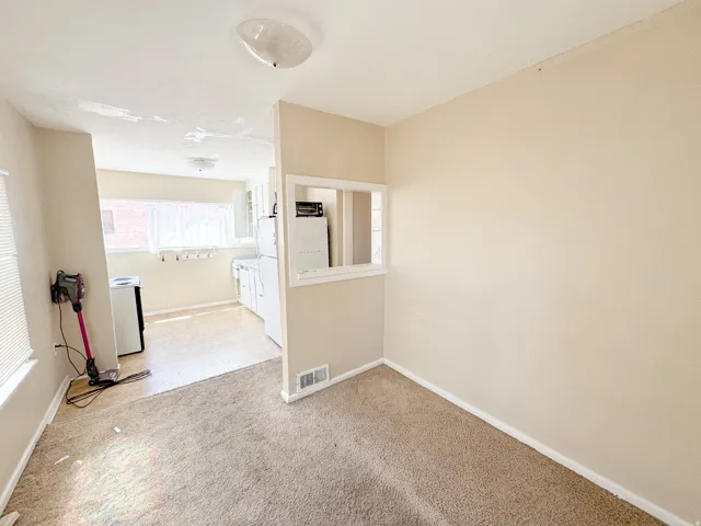 Carpeted room with a pass-through window to the kitchen
