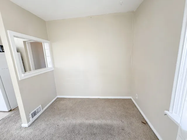 Neutral wall paint, light brown carpeting, white trim, and a pass-through window