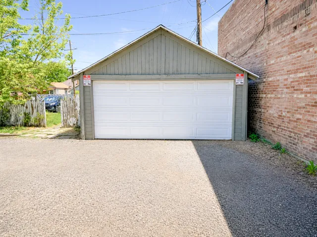 Two-car garage with a white panel door, featuring a pitched roof and light green siding
