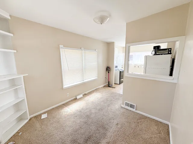 Carpeted living area featuring a built-in shelving unit and two windows with blinds