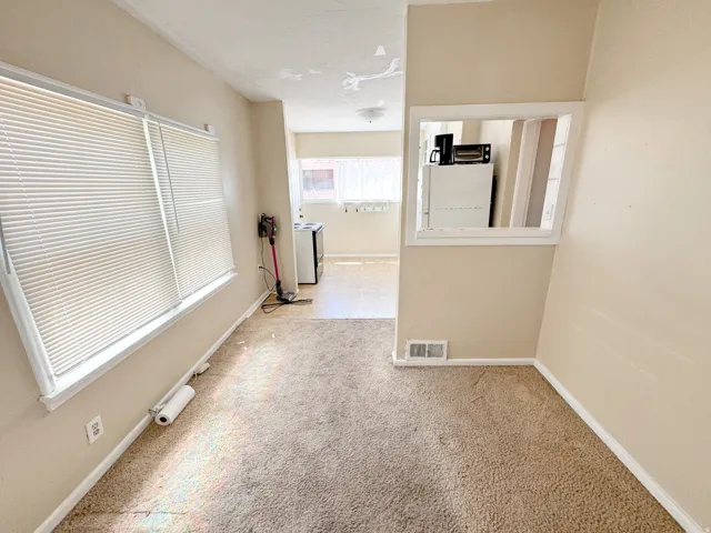 Carpeted room with a wide window featuring blinds