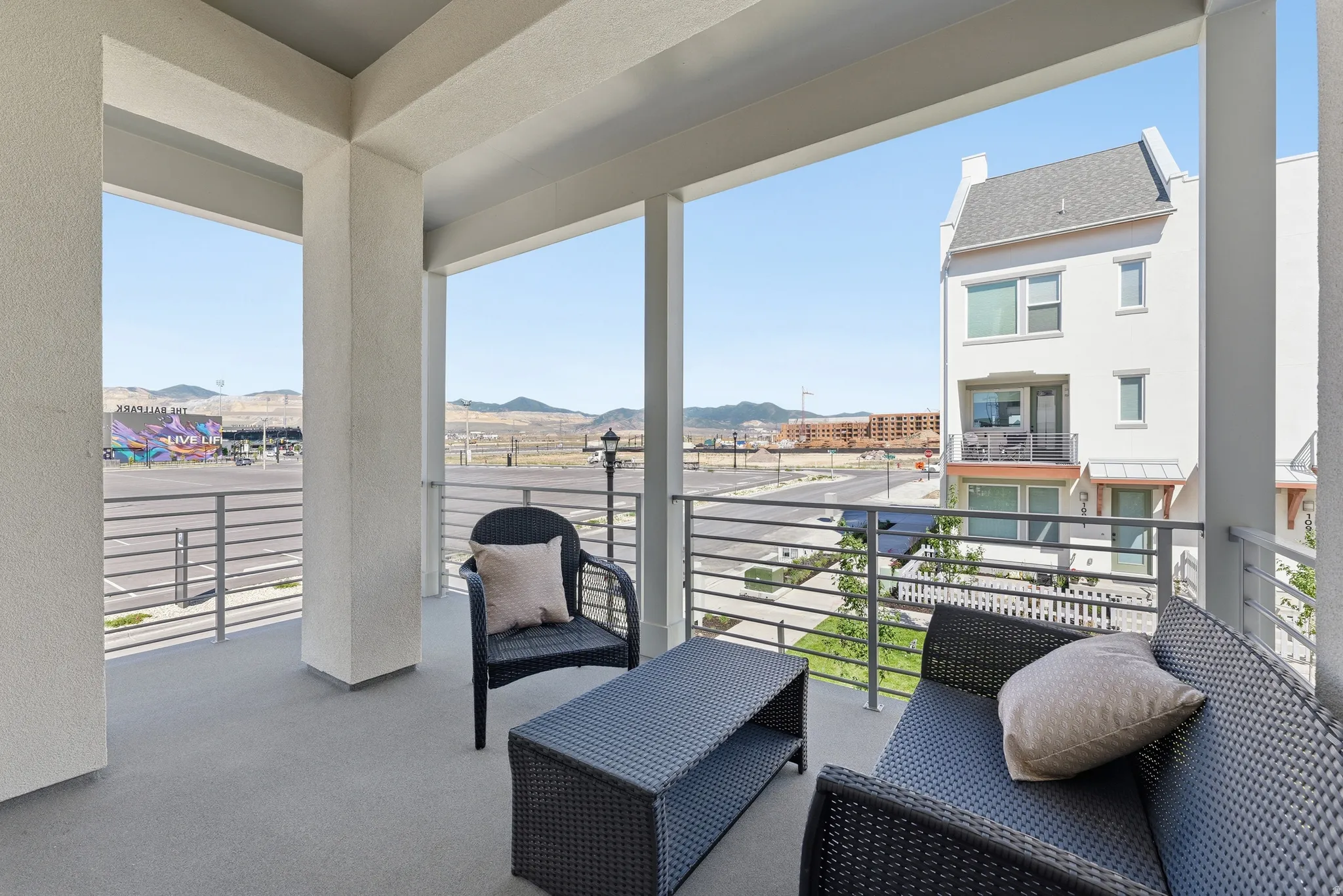 Expansive covered patio featuring a concrete floor, stucco columns, and metal railings