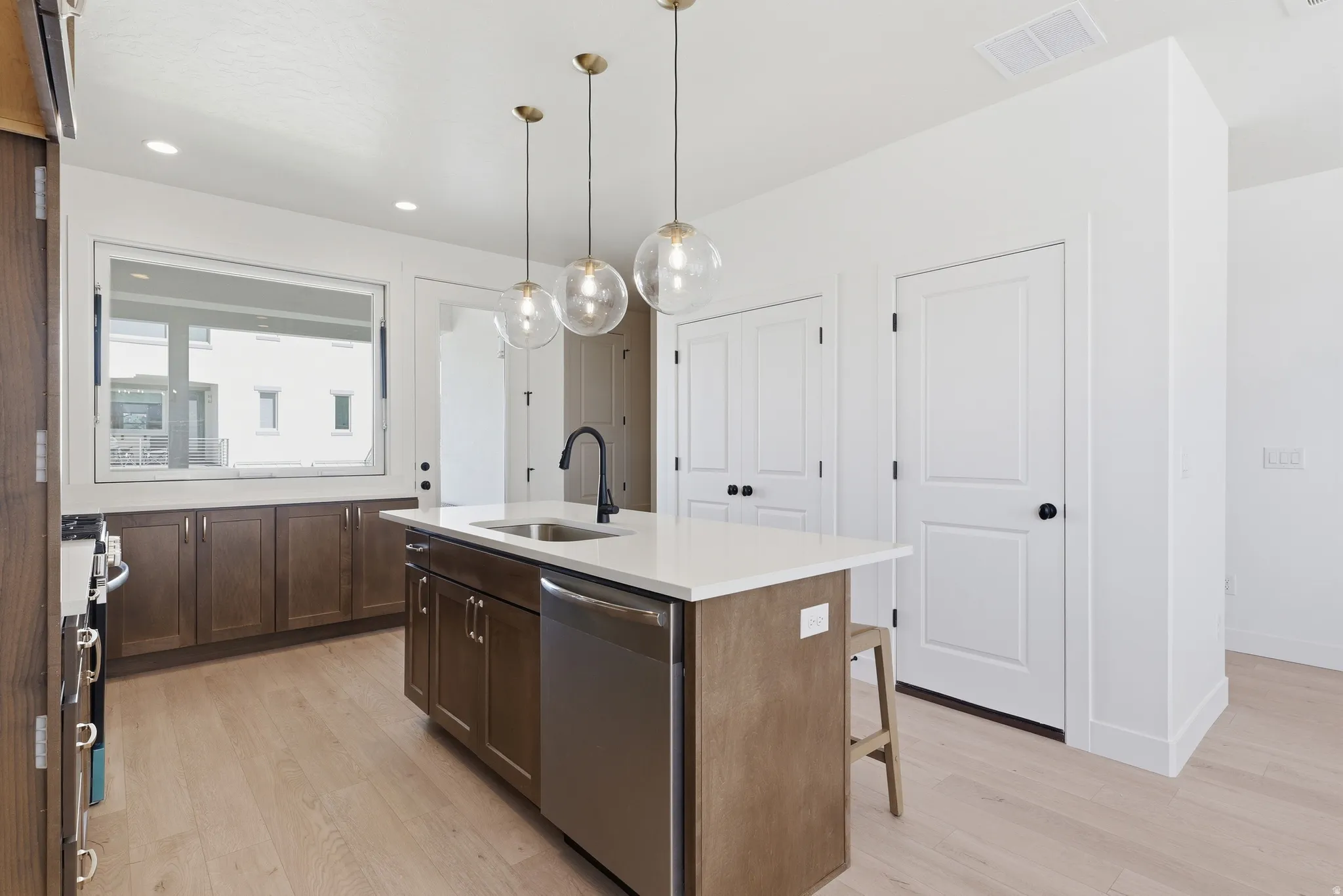 Contemporary kitchen featuring a central island with an undermount sink and a stainless steel dishwasher