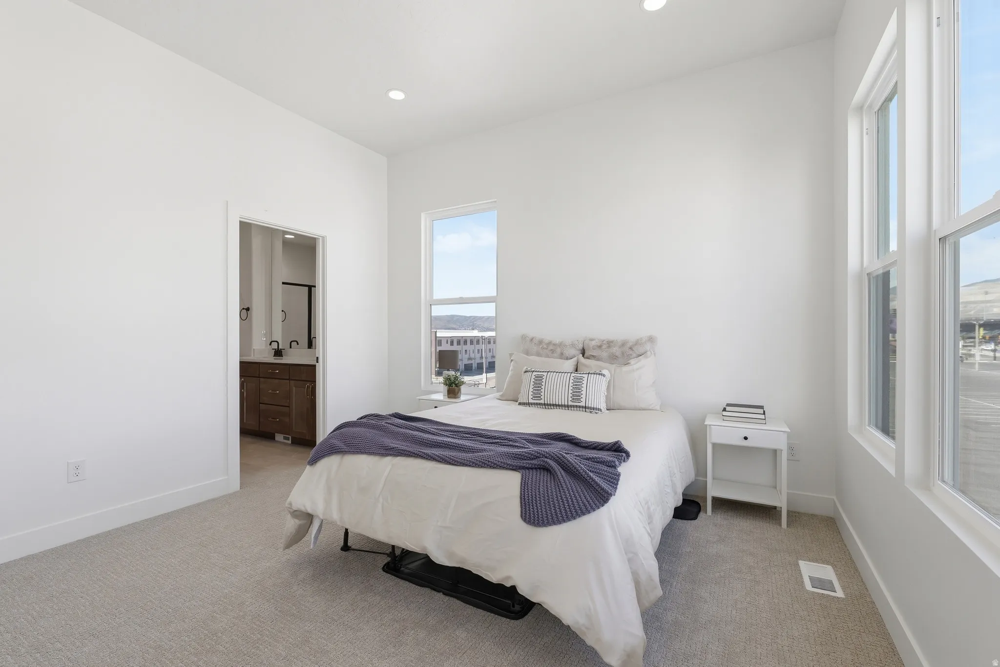 Carpeted bedroom featuring white walls, recessed lighting, and multiple windows