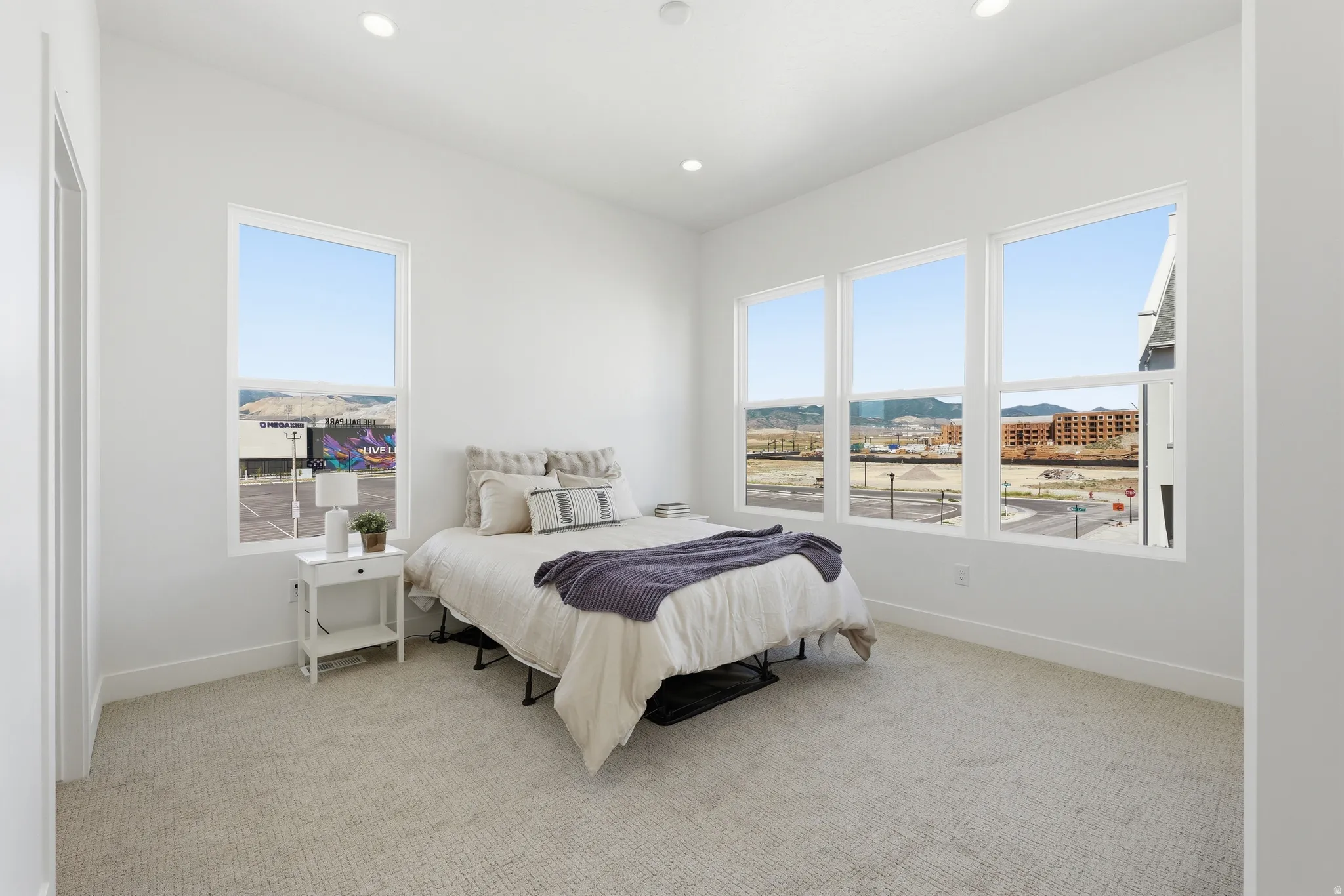 Room with expansive windows showcasing distant architectural elements and mountainous terrain
