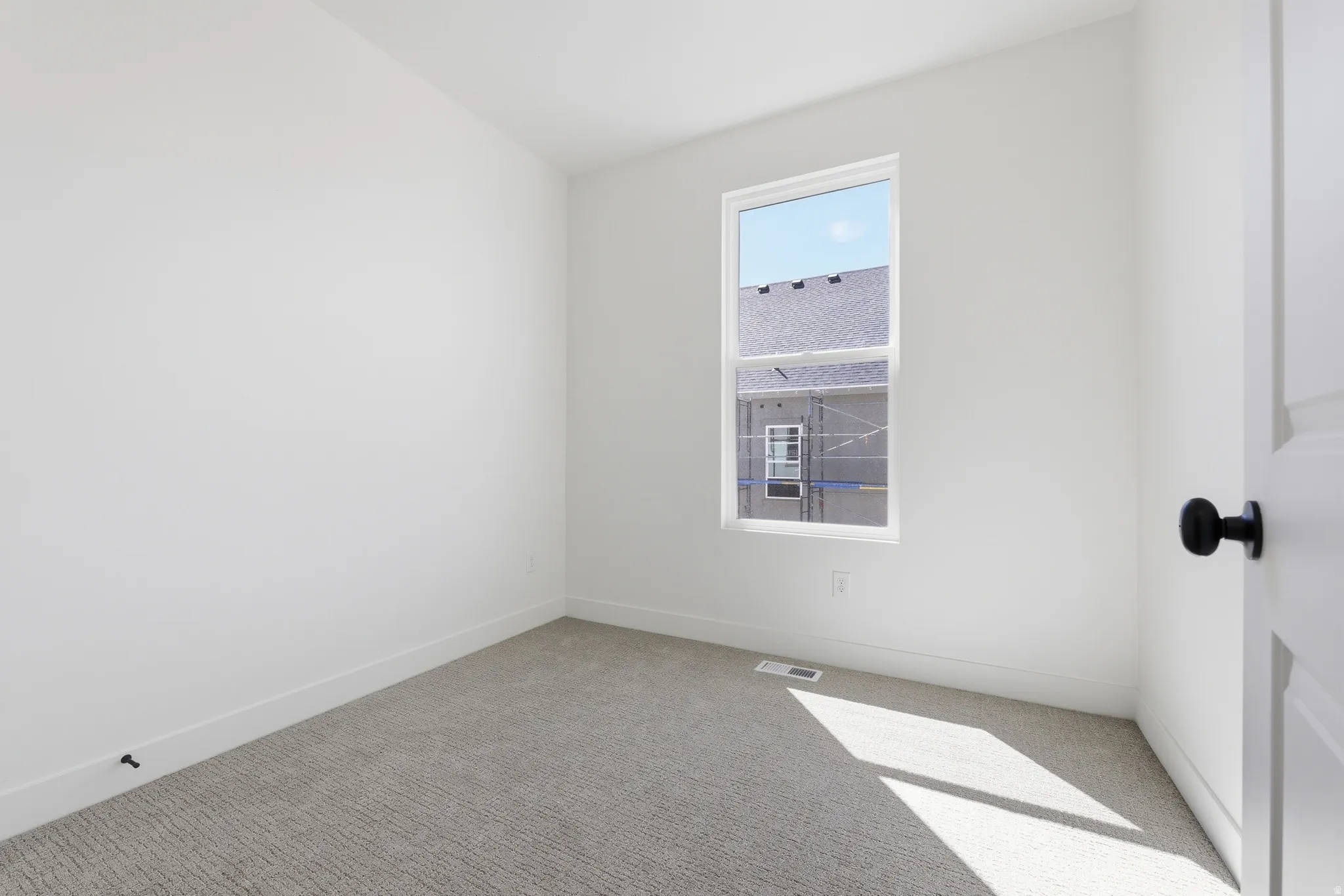 Bedroom featuring light grey carpet, white walls, and an egress window