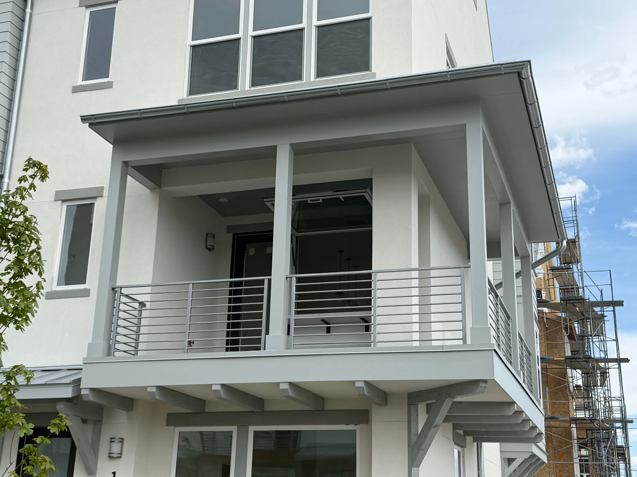 Upper-level balcony featuring contemporary horizontal metal railings, square columns, and grey soffit detailing