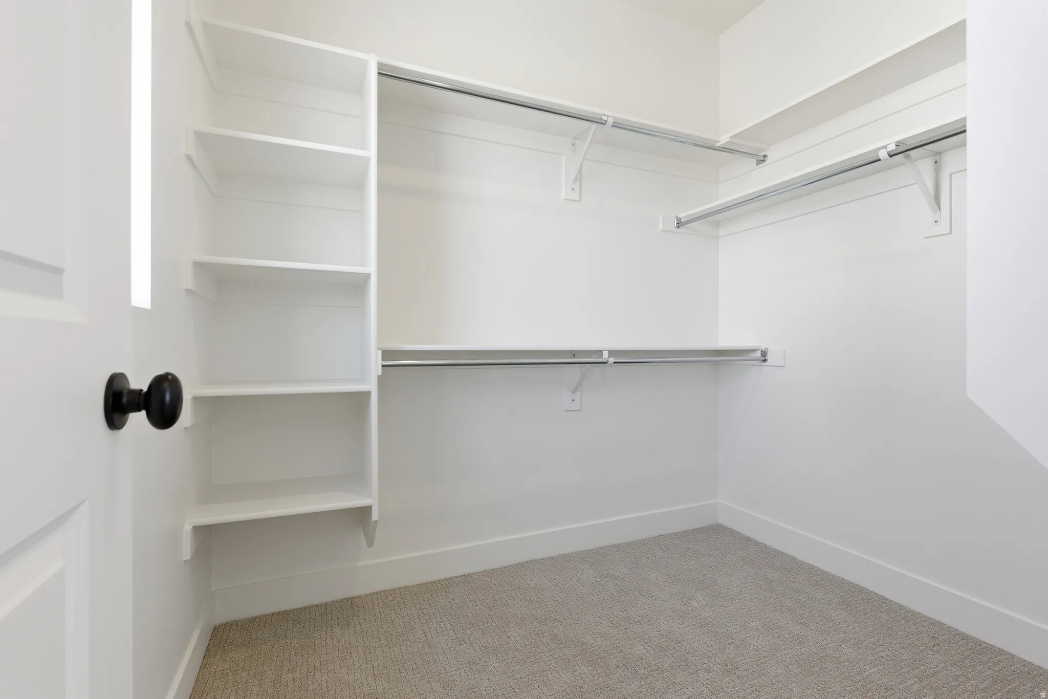 Walk-in closet with integrated white shelving and multiple chrome hanging rods