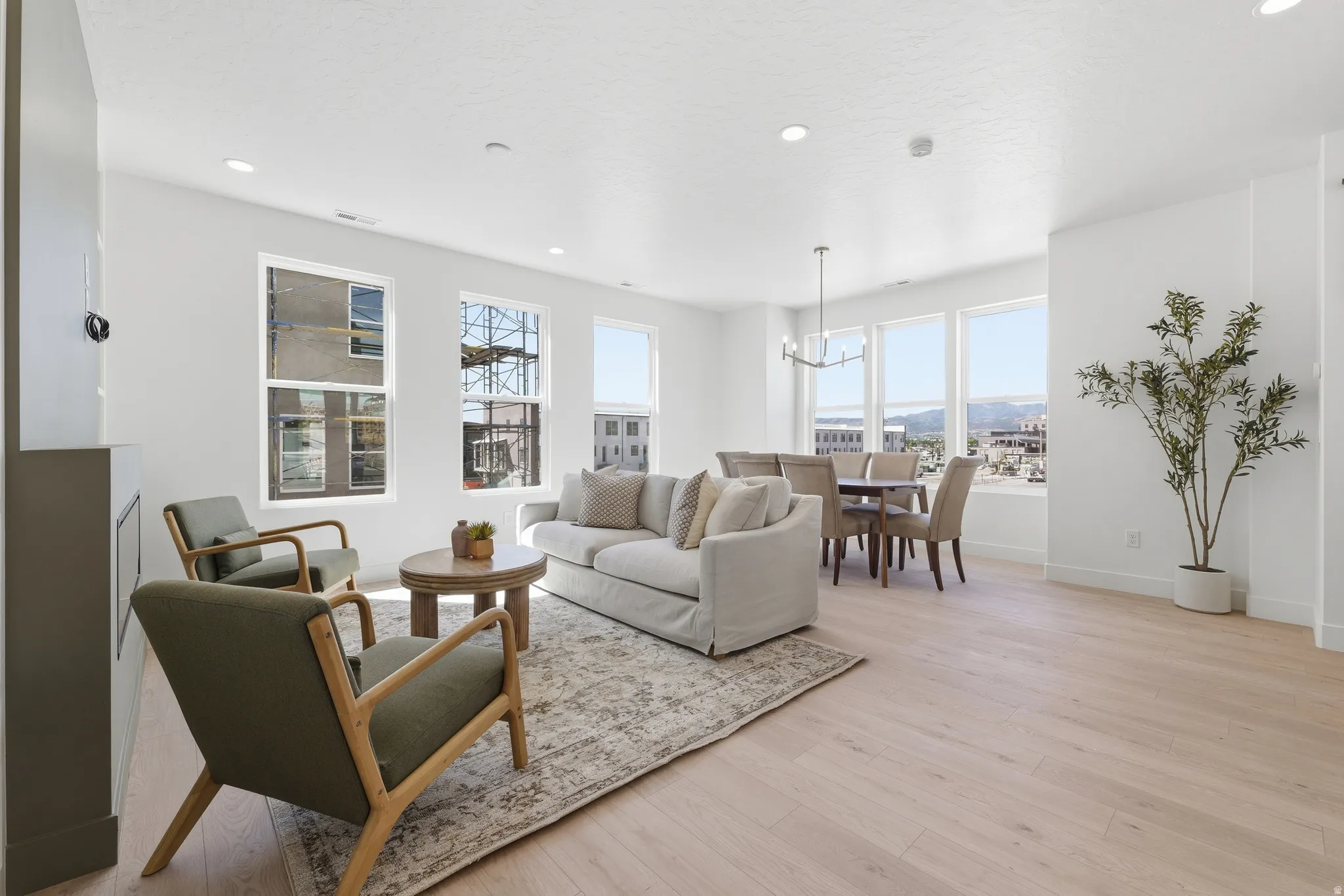Spacious open-concept living and dining area featuring light wood-finish flooring and recessed lighting
