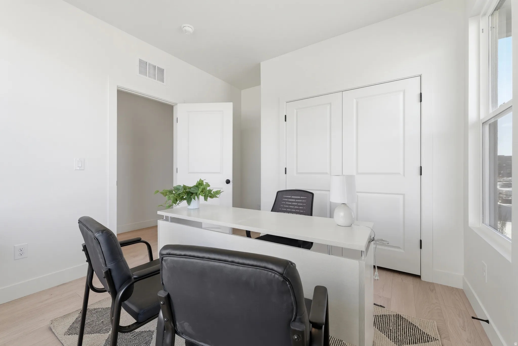 Bright interior space featuring light wood-finish flooring, white walls, and a large window