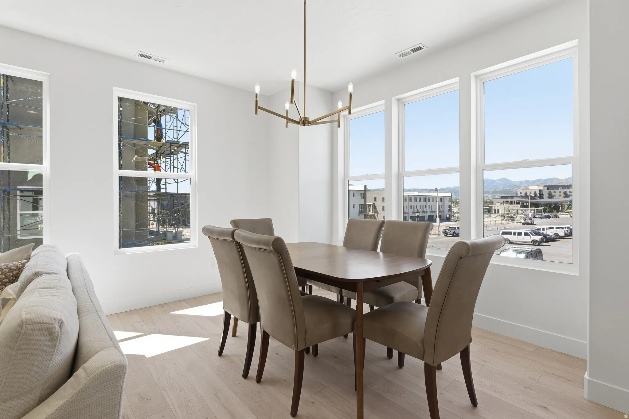 Bright dining space featuring wood-finish flooring, a contemporary chandelier, and multiple large windows