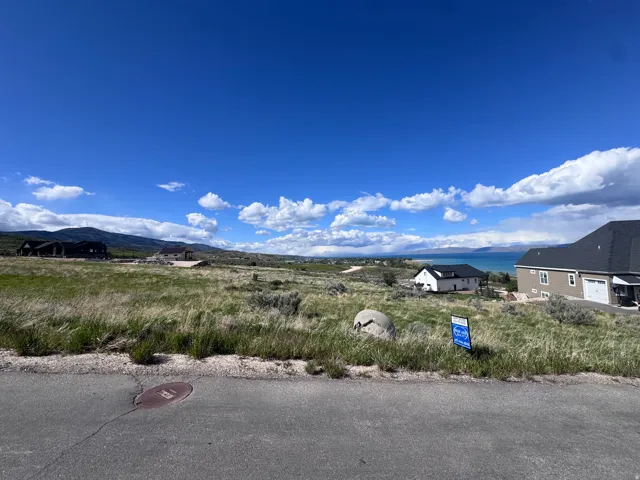 Expansive undeveloped land featuring a gentle slope, distant water body, and mountain backdrop