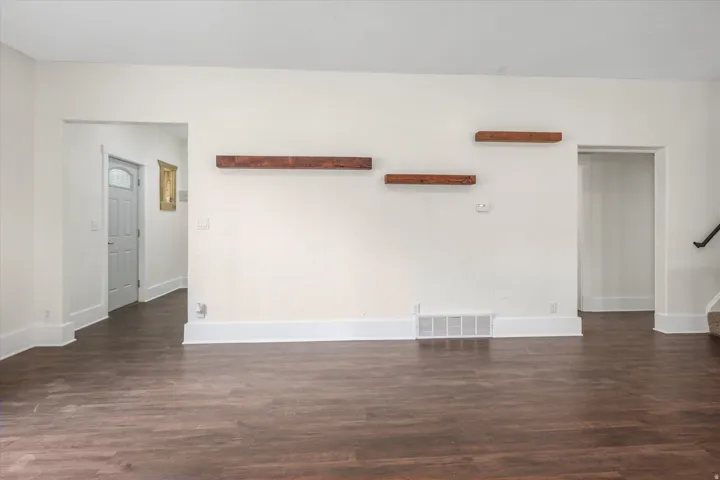 Spacious interior with wood-finish flooring, white baseboards, and neutral wall paint