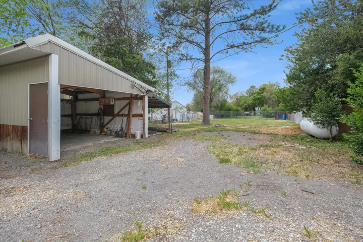 Large gravel driveway with a detached metal outbuilding featuring a covered bay and side entry door