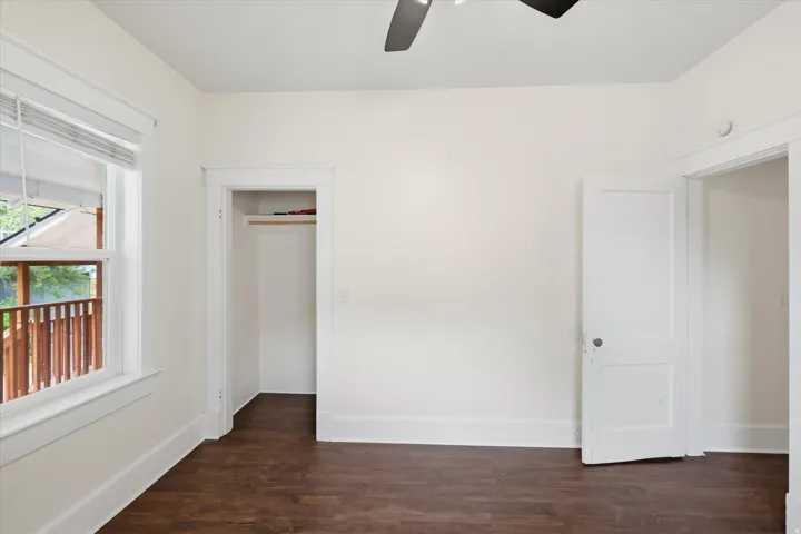 Spacious room featuring wood-finish flooring, a ceiling fan, and a window with blinds