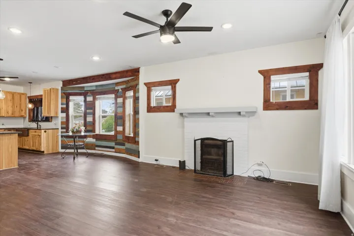 Spacious room featuring wood-finish LVP flooring, white walls, and a white brick fireplace with a mantle