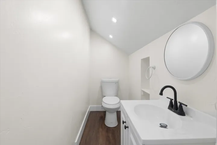 Compact bathroom featuring a white vanity with integrated sink, matte black faucet, and a round wall-mounted mirror