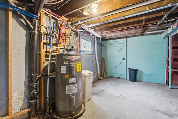 Basement utility area featuring a water heater, visible plumbing, exposed ceiling joists, and a concrete floor