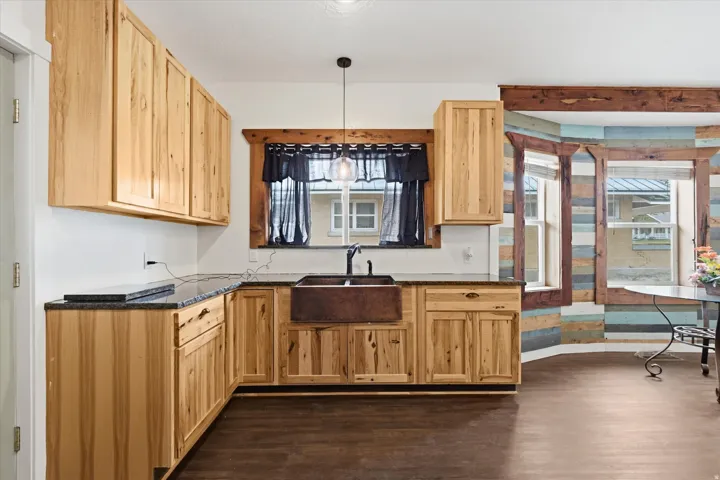 Kitchen featuring light wood cabinetry, dark countertops, and a prominent copper farmhouse sink with a black faucet