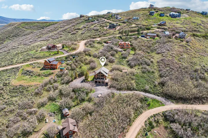 Sloping hillside property featuring a multi-level residence with extensive natural landscaping and unpaved access roads