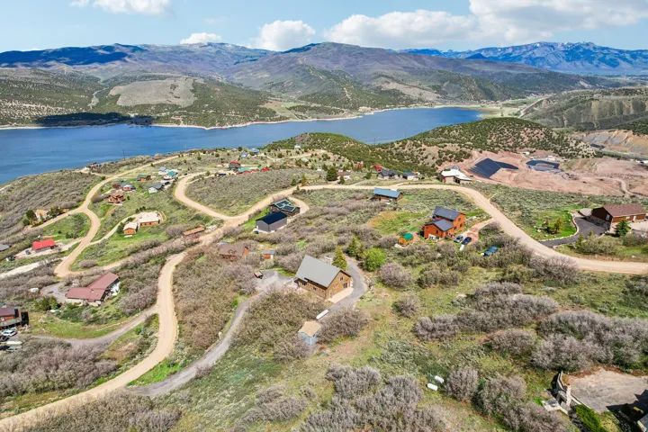 Aerial perspective of a mountainside community featuring various architectural styles, winding dirt roads, and abundant natural foliage