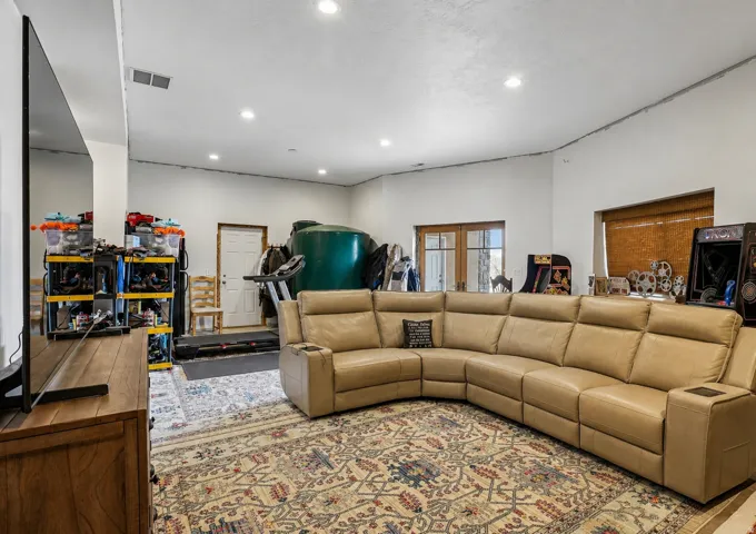 Spacious entertainment room featuring recessed lighting, a large area rug, and French doors