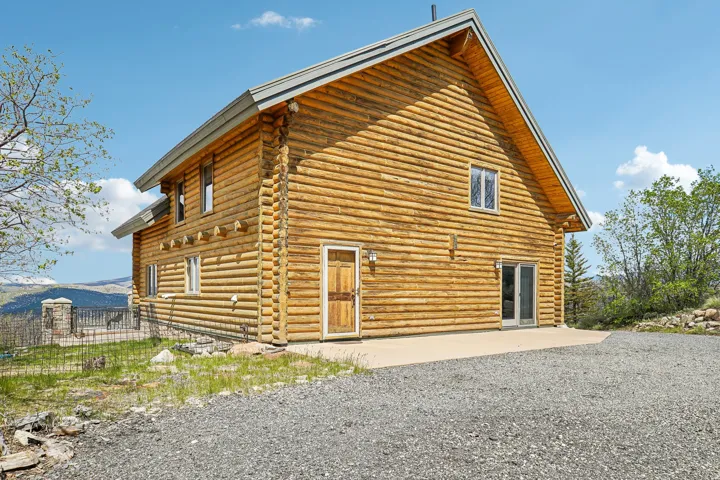 Log cabin exterior featuring a pitched roofline, exposed log construction, a solid wood entry door, and sliding glass doors