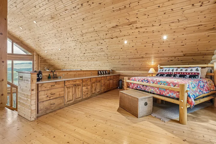Spacious loft area featuring extensive wood-finish flooring, wood-paneled walls, and a wood-paneled sloped ceiling with recessed lighting