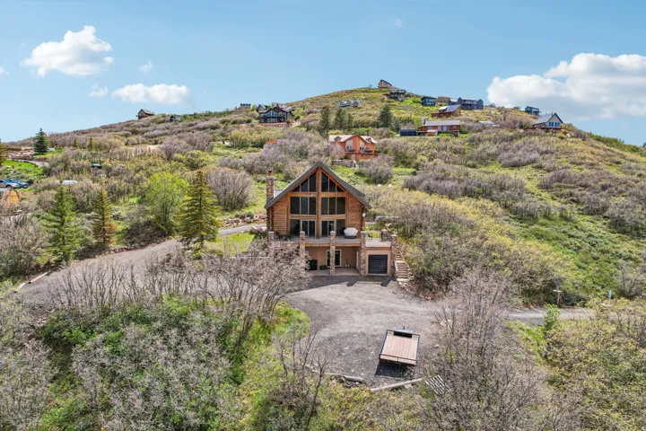 Rustic-modern residence featuring a prominent A-frame design, extensive window walls, and wood-finish siding