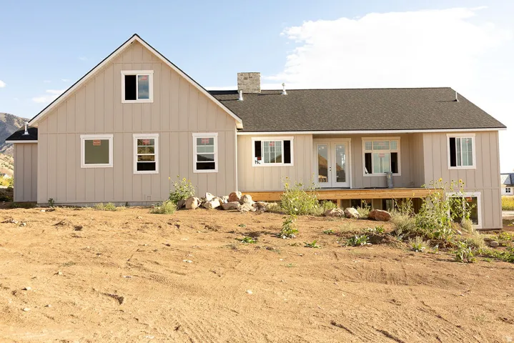 Board and batten siding, dark shingle roof, wood deck, and white-framed windows