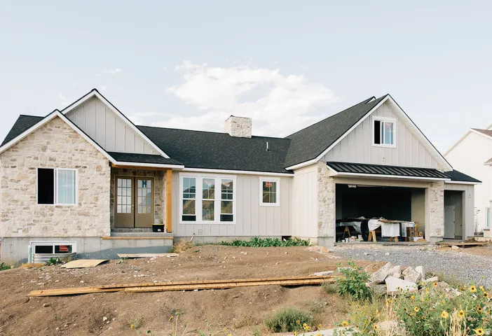 Stone and board-and-batten exterior with a dark shingle roof