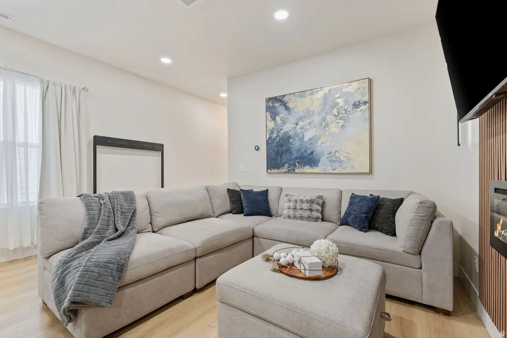 Living area featuring light wood-finish flooring, recessed lighting, a built-in vertical slat panel accent wall, and a built-in electric fireplace